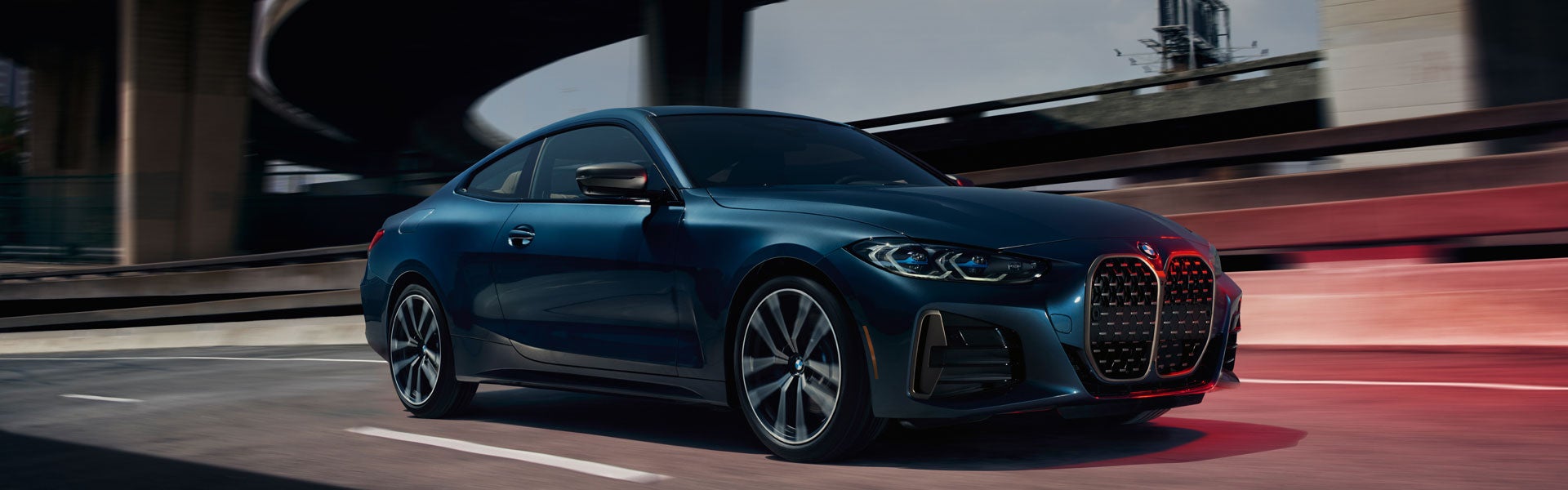 A Bernina Gray Amber Effect BMW 7 Series driving across city bridge.