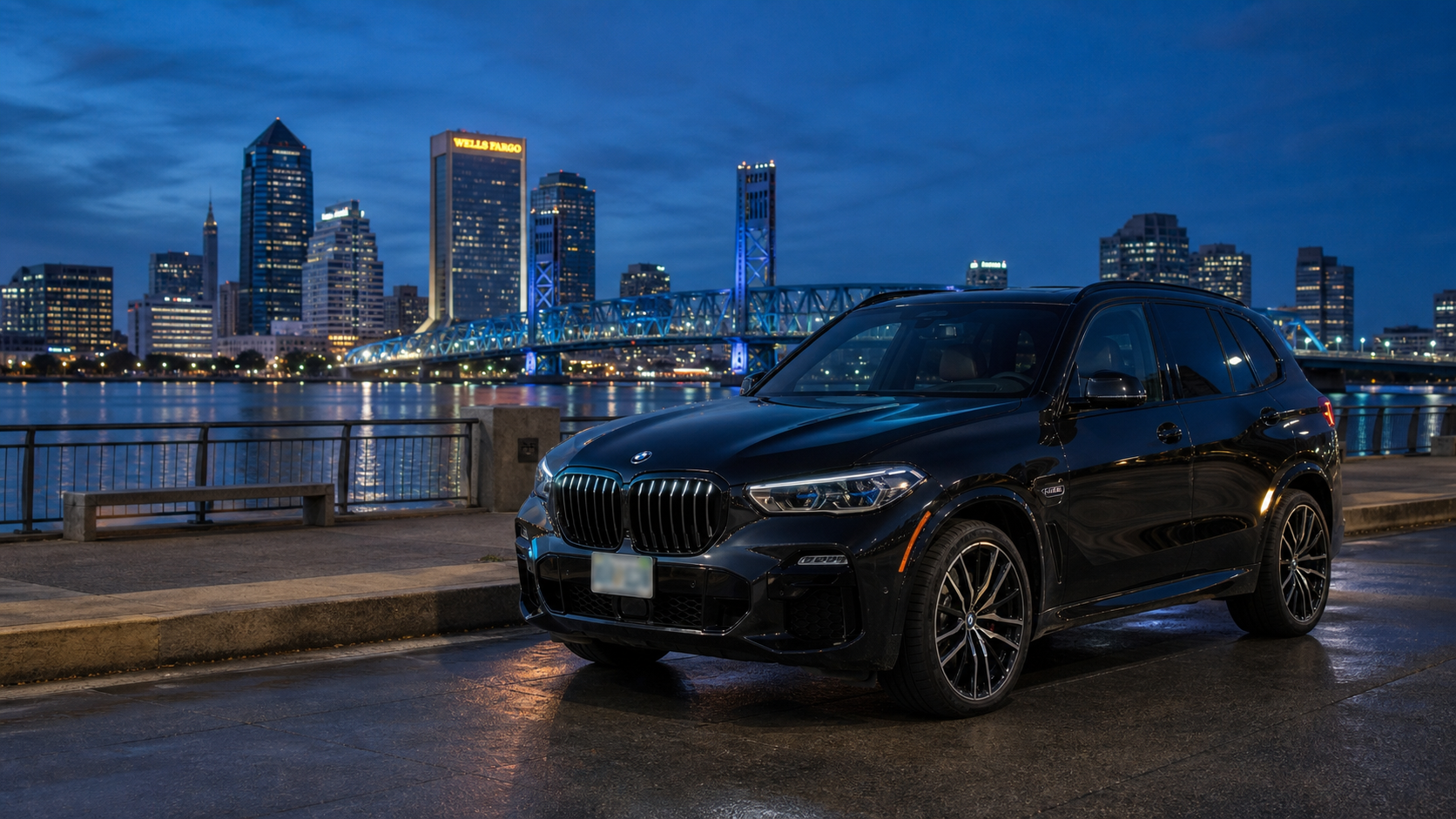 BMW X5 M60i parked in downtown Jacksonville with the city skyline at dusk